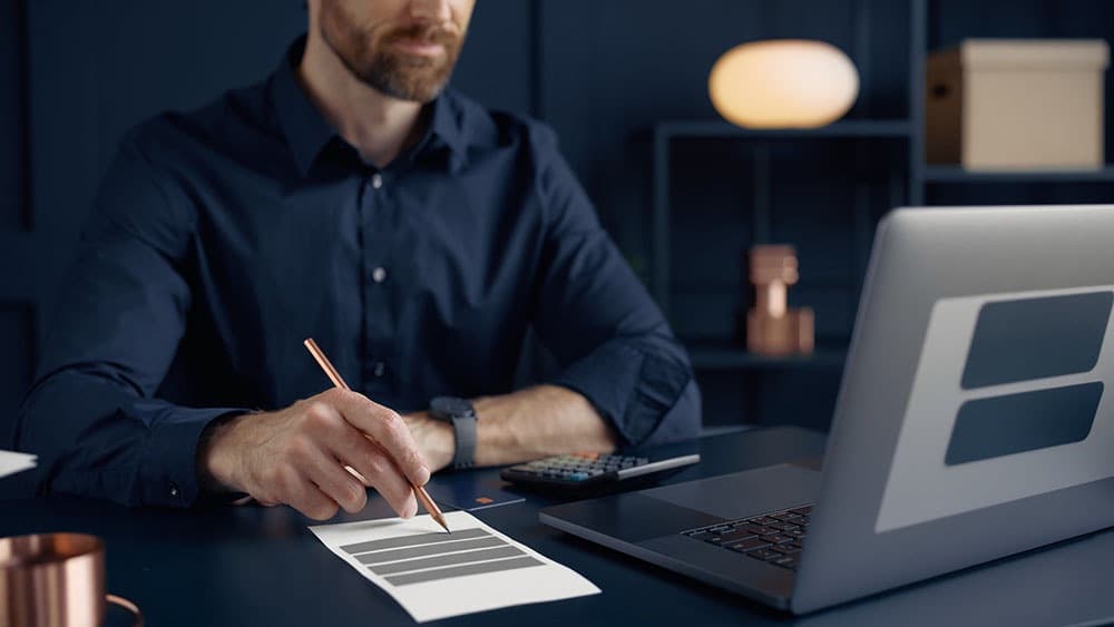Business owner reviewing payment processing fees and expenses using a receipt calculator and laptop